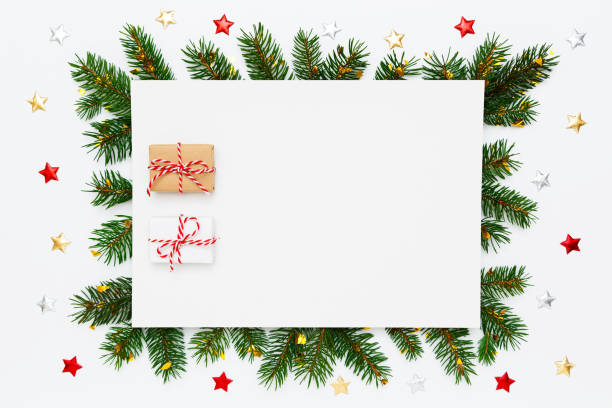 istock Christmas, New Year holiday layout with copy space. Blank white paper with two small Christmas gifts in frame of natural fir tree branches and decorations on white flat lay background 1417748430