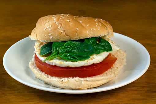 breakfast sandwich  consiting of fried egg tomato and spinach