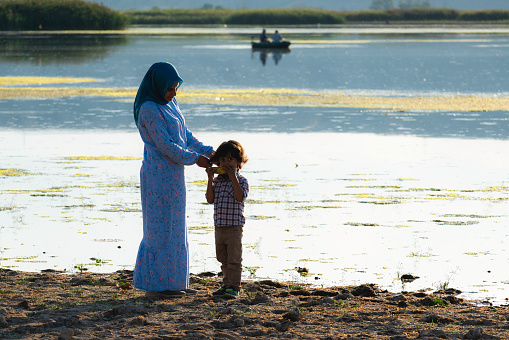 mother spending time by the river with her son. dad is boat fishing on the river. green algae on the water surface provided a beautiful color transition.
Taken with a full-frame camera in daylight