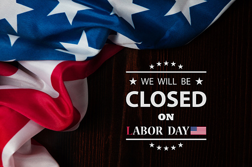 Labor Day Background Design. American flag on a wooden table with a message. We will be Closed on Labor Day.