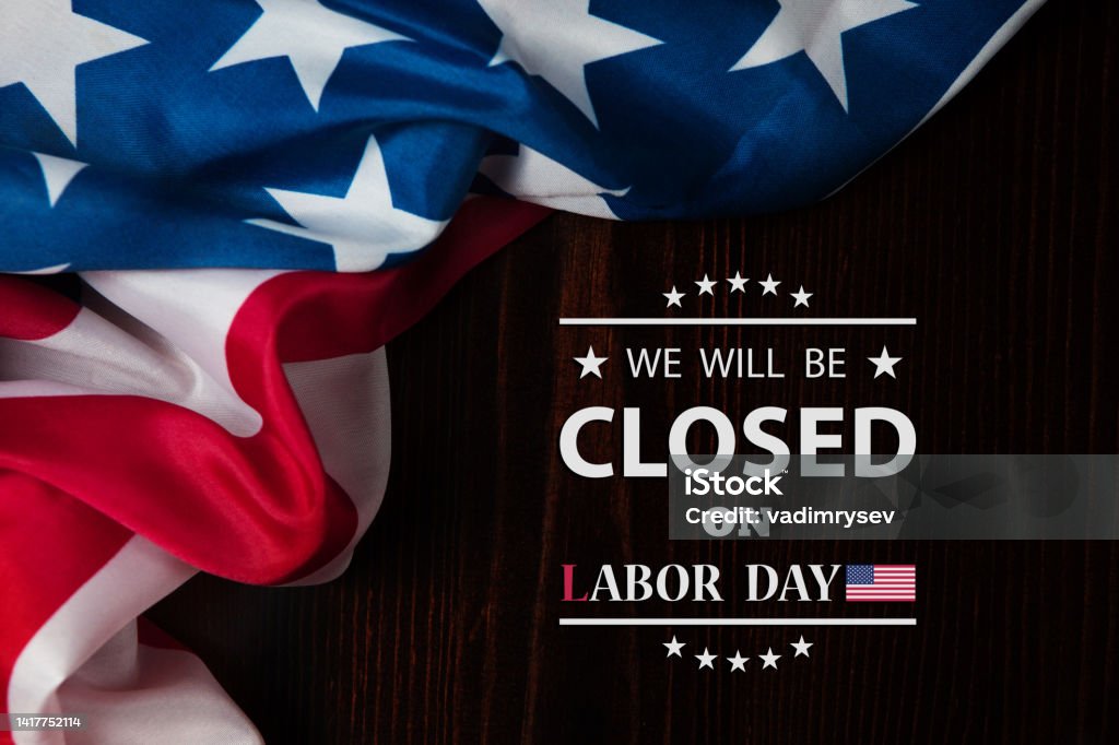 Labor Day Background Design. We will be Closed on Labor Day. Labor Day Background Design. American flag on a wooden table with a message. We will be Closed on Labor Day. Labor Day - North American Holiday Stock Photo