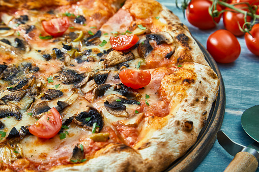 Pizza on a rustic kitchen or restaurant table, with fresh vegetables