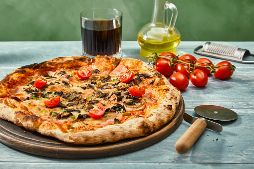 Colorful Pizza on a rustic kitchen or restaurant table, with olive oil and cherry tomato