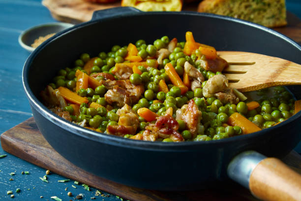 鍋にニンジンと鶏肉を入れたグリーンピース - legume wooden spoon food kitchen utensil ストックフォトと画像