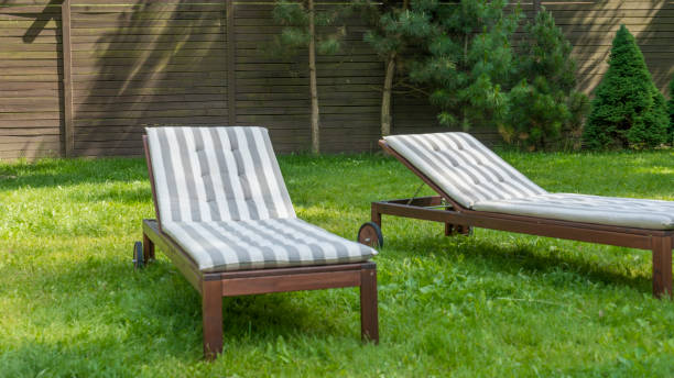 istock Lounge chairs on the backyard in a beautiful garden. Two empty sunbeds on the grass. 1417762144