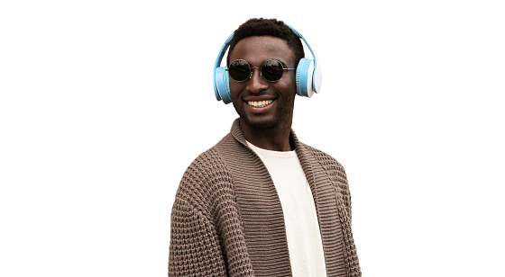 Portrait of happy smiling african man in wireless headphones listening to music looking away isolated on white background