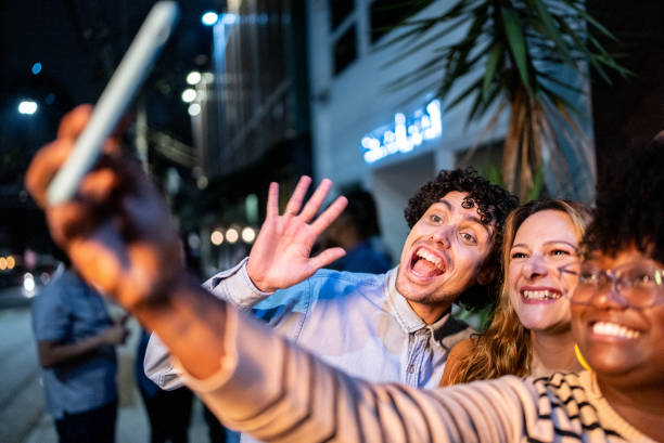 istock Friends taking a selfie or filming using mobile phone outdoors 1417765641