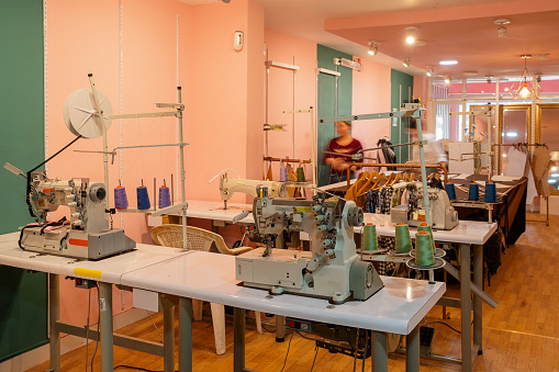 Sewing workshop with a raw of tables and machines to work and people around