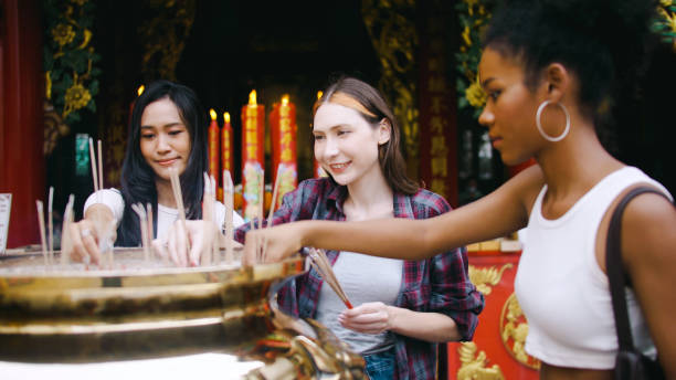 a group of multi-ethnic female friends praying at a chinese shrine in bangkok, thailand. - choicesea 個照片及圖片檔