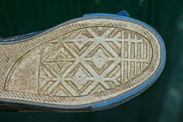 white gray rubber sole of one dirty boot with a pattern on a green background