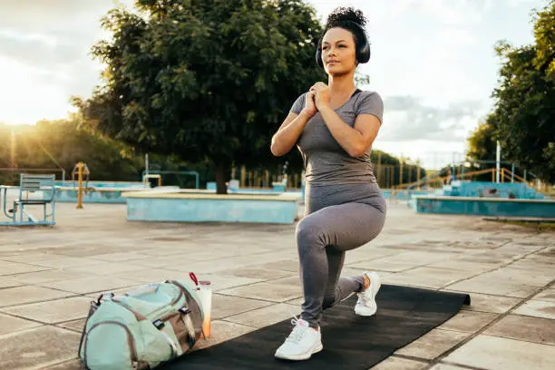 Photo of Fitness girl doing lunge in urban park