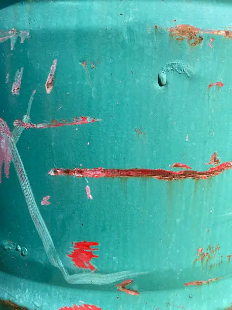 Close-up of rusty blue metal, with horizontal red paint splash in the middle.