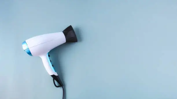Modern hairdryer with diffuser on  light blue  large background  for banner. Hair care and styling concept. Copy space