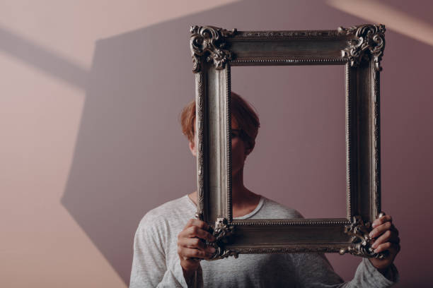 istock Portrait young man standing with picture frame at studio. 1417786949