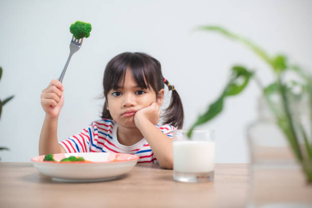 concept de nutrition et d’habitudes alimentaires saines pour les enfants. les enfants n’aiment pas manger de légumes. la petite fille mignonne refuse de manger des légumes sains. - anger child furious asian ethnicity photos et images de collection