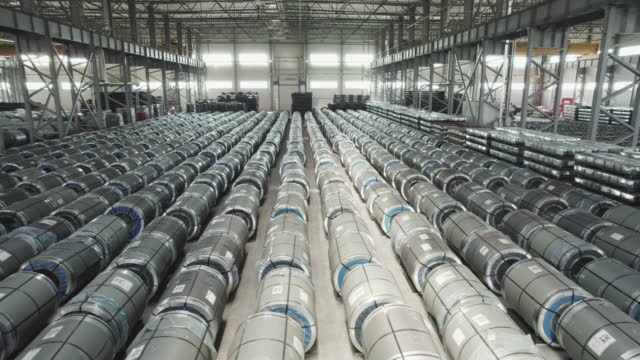 Industrial warehouse of a metallurgical enterprise. Rolled metal products are stored in rows in a warehouse.