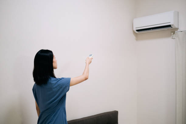 istock Woman turning on air conditioner 1417807155