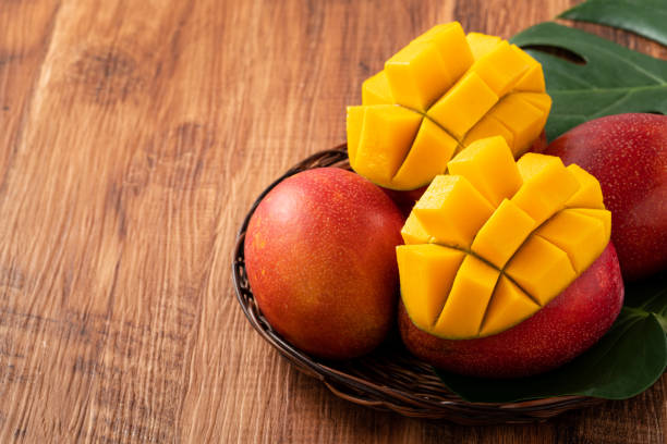 istock Mango. Fresh mango fruit with leaves over dark wooden table background. 1417819936