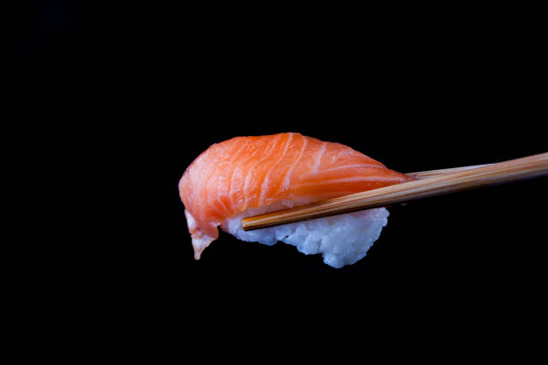 istock A Salmon sushi being held by wooden chopsticks 1417821803