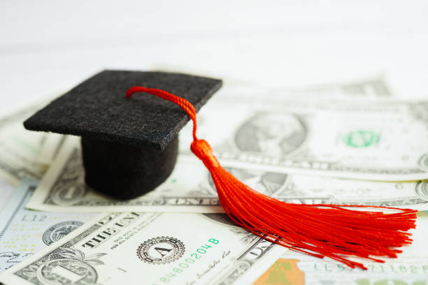istock Graduation gap hat on US dollar banknotes money, Education study fee learning teach concept. 1417824257