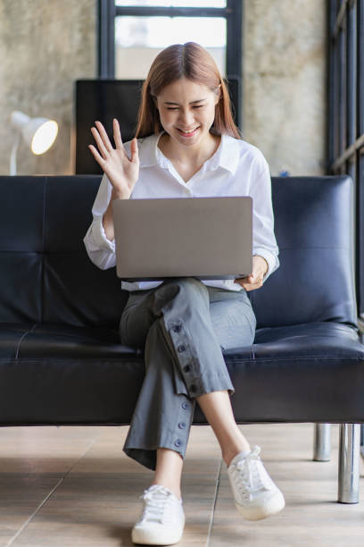 istock Asian woman sitting on sofa with laptop working online 1417824429