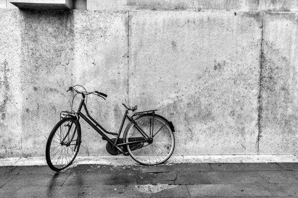 A picture of a lonely pink bike standing in the typical street in Stockholm. The bike looks to be modern in a retro style. The background is black and white.