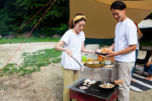 istock Young couple barbecuing at a campsite 1417834492