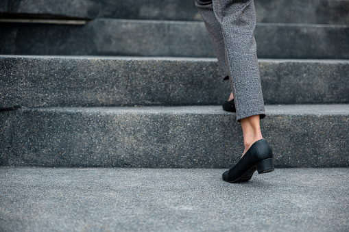Primeros planos de piernas de mujer de negocios se apresuran a caminar por la escalera photo