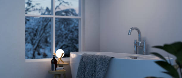Modern comfortable bathroom in the evening with bathtub and romantic warm light from lamp stock photo