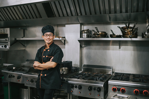 portrait success asian Chinese chef looking at camera smiling in commercial kitchen