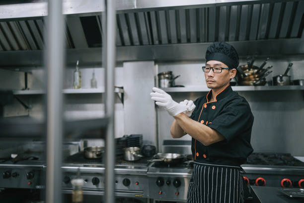 Asian Chinese Chef getting ready put on latex glove in commercial kitchen Asian Chinese Chef getting ready put on latex glove in commercial kitchen daily routine putting on latex gloves stock pictures, royalty-free photos & images
