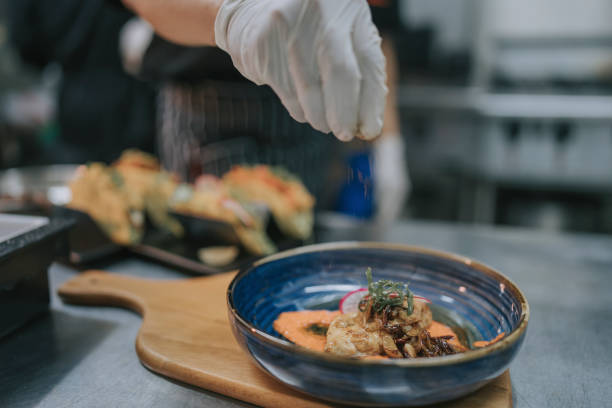 istock Close up chef sprinkling sesame seed finishing touch on cuisine in kitchen 1417840021