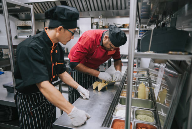 istock Asian Chinese male trainee kitchen crew learning from master chef preparing taco Mexican food in commercial kitchen 1417840539
