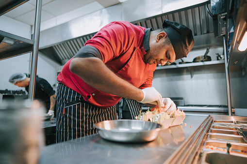 Asian Indian Chef preparing taco Mexican food in kitchen