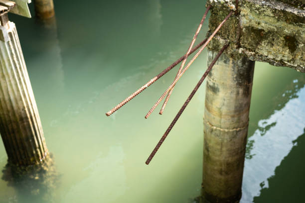 Rustic steel bar on concrete pillar building structure over the water surface. Building object photo, selective focus.