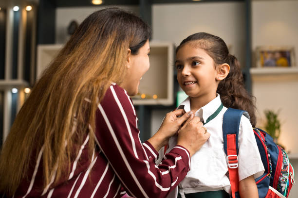 Mother getting her daughter ready in school uniform at home