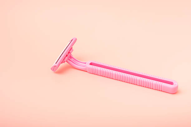 Disposable pink razor on a pastel pink background