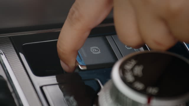 Driver finger pushing the parking brake button. Electronic parking brake with Auto-hold in modern car. Transportation and vehicle concept.