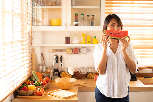 Girl eating watermelon in the kitchen.