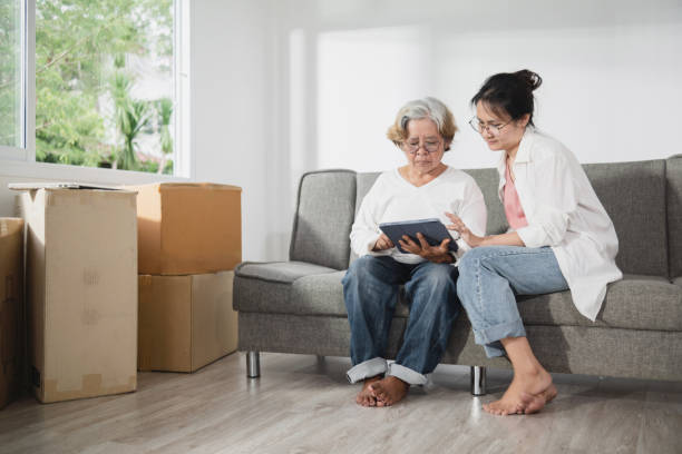 concetto di trasloco e nuova casa, donna anziana asiatica e figlia. parlare e usare un tablet. - grandparent senior adult child reading foto e immagini stock