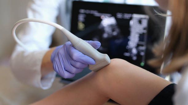 Doctor conducting ultrasound examination of knee joint in child closeup stock photo