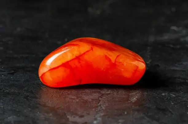 Carnelian mineral on a black concrete background. The concept of using minerals and crystals in astrology and alternative or complementary medicine