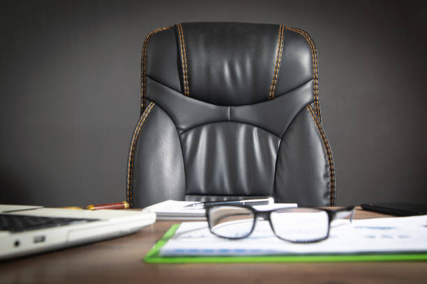 istock Focus on black leather chair with a office workplace. 1417856642