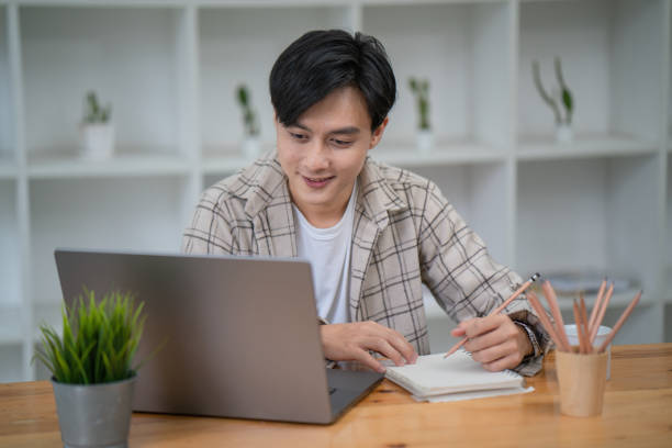 istock Handsome young businesspeople working with laptop computers and writing new ideas in a notebook. 1417857963