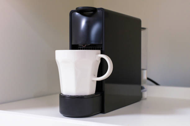 istock Capsule coffee machine and white mug close-up on a gray background. 1417858192