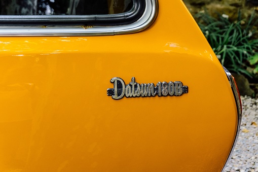 Barcelona, Spain - August 14, 2022. Datsun 180B orange color, model of the Bluebird 610 series of medium size produced between 1971 and 1976. Close-up view of the model name