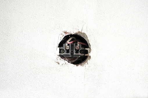 Old open socket. Old socket without the covering on the white concrete wall. Renovation concept