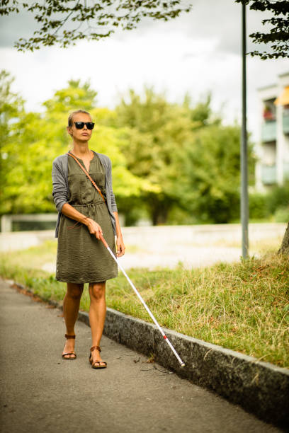 istock Blind woman walking on city streets, using her white cane 1417863105