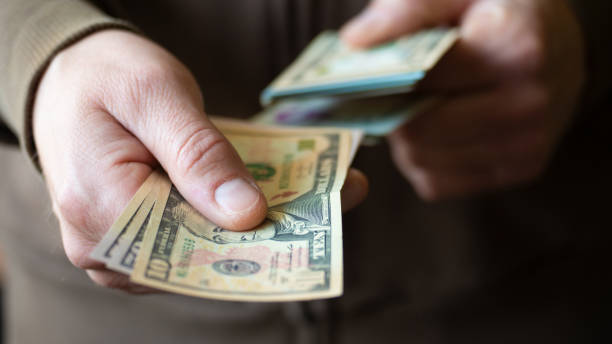 istock White man giving several dollar bills closeup 1417863792