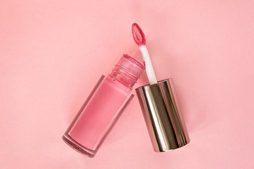 Pink cream lip gloss open jar on pink background